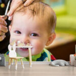 Smiling baby cutting hair