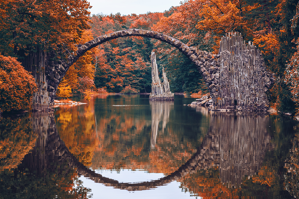 A stone arch over water with trees in the background
