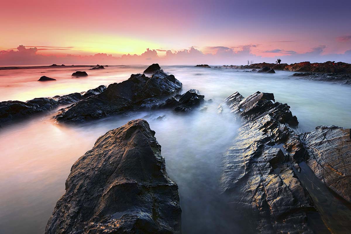 A rocky beach with a person standing on it