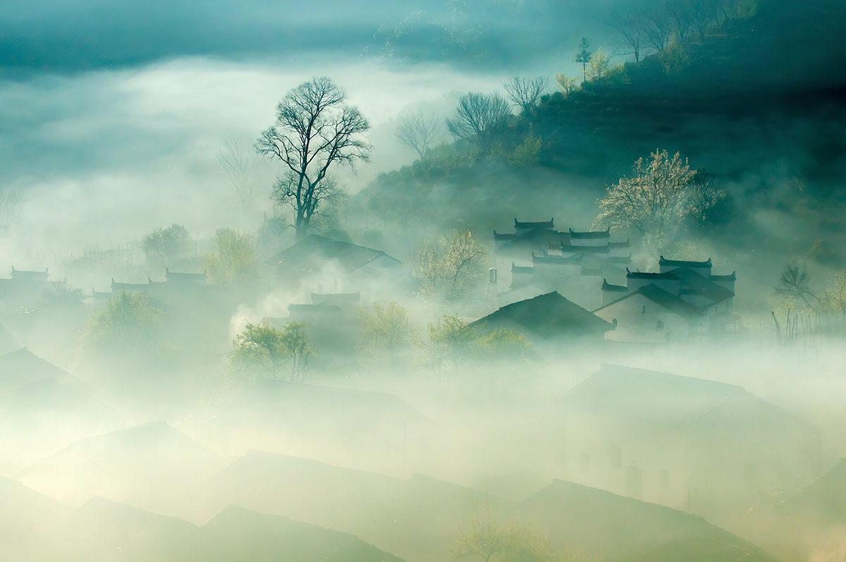 A foggy landscape with houses and trees