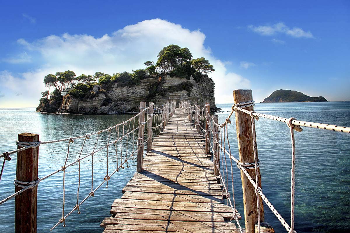 A wooden bridge over water with a small island in the background