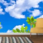 A tree branch with green leaves and blue sky with clouds