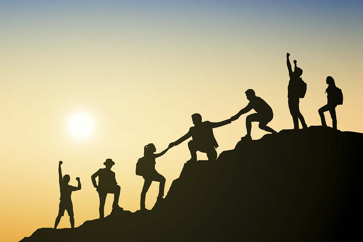 Silhouette of people climbing a mountain