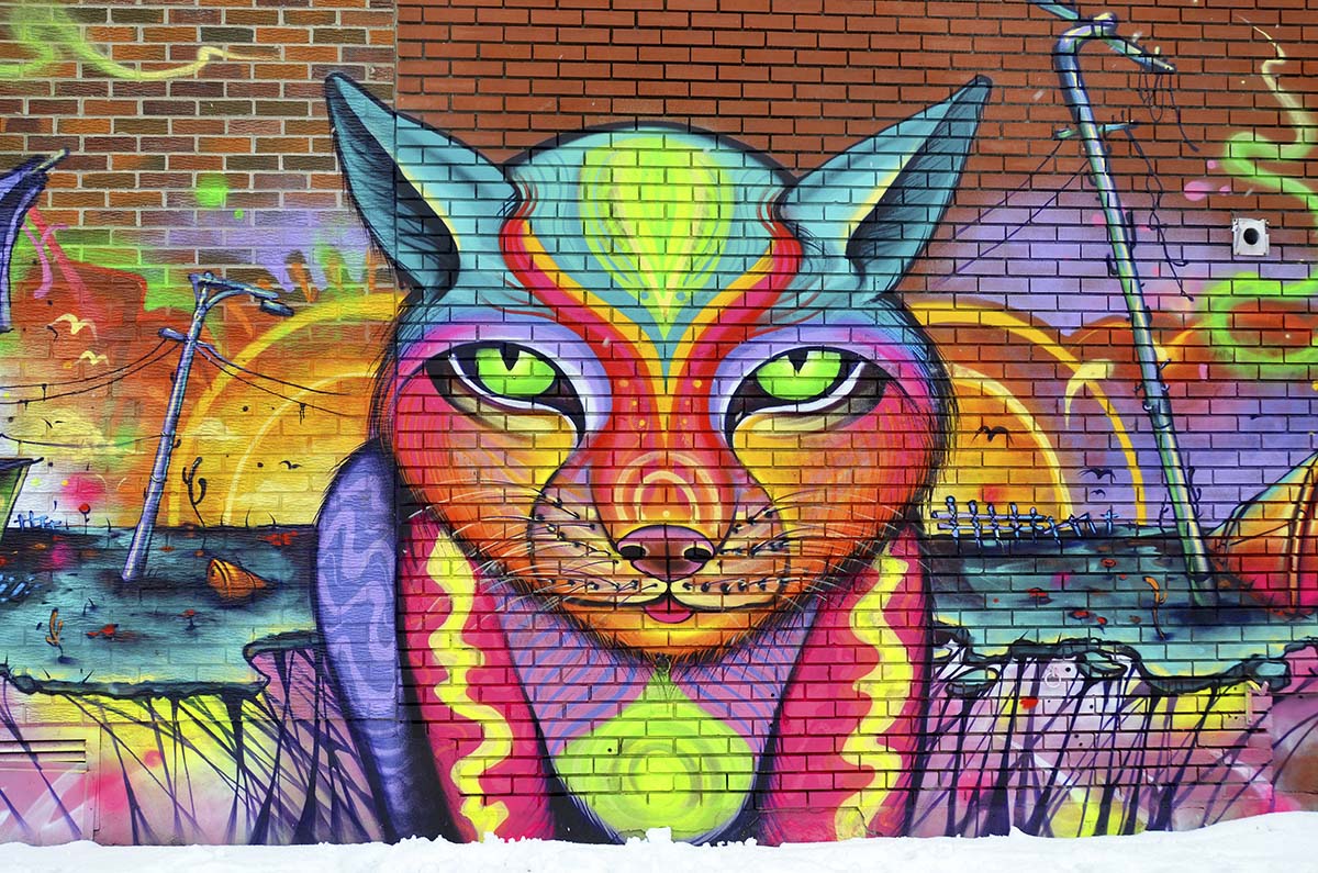 A colorful cat mural on a brick wall